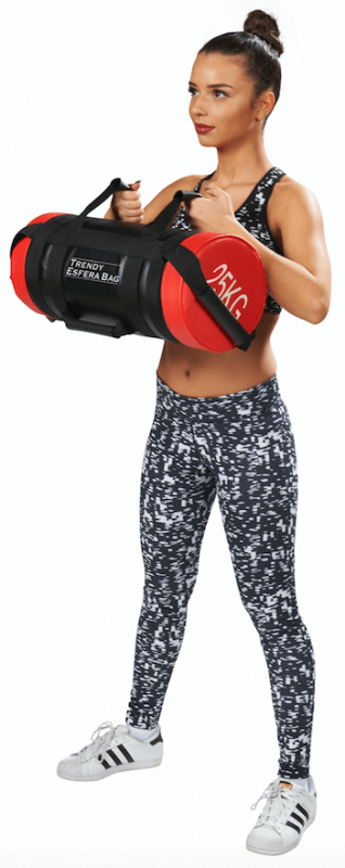 A woman in sportswear, with a plait and patterned leggings, holds a black cylindrical Esfera weight bag in front of her with both hands on the handles, ready for a range of strength and cardio training exercises.