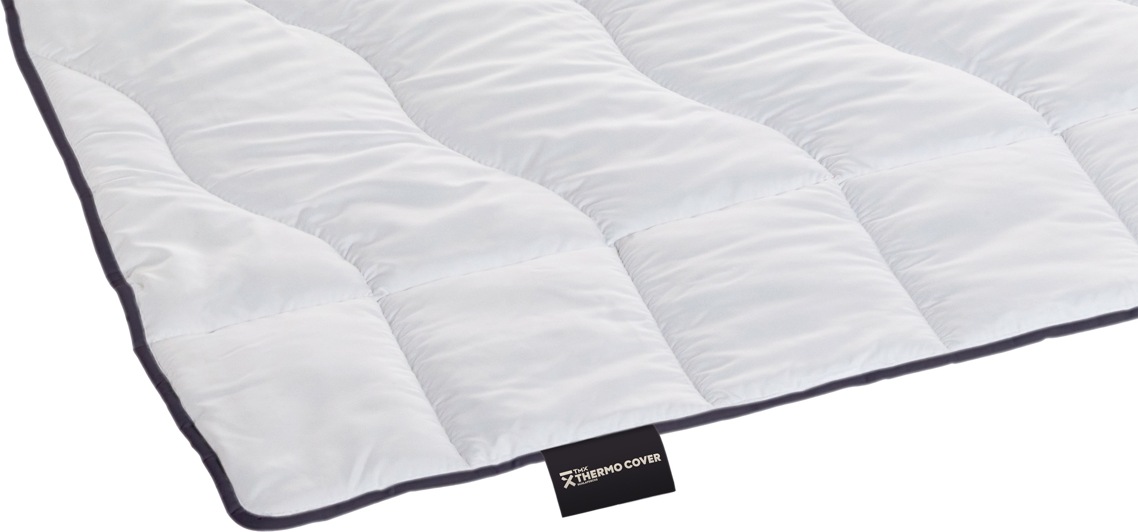 White, quilted duvet with soft, slightly raised panels and a dark grey border. Black ‘TMX® Thermo Cover’ label at the bottom. High-quality workmanship; breathable and temperature-regulating for a comfortable night’s sleep.