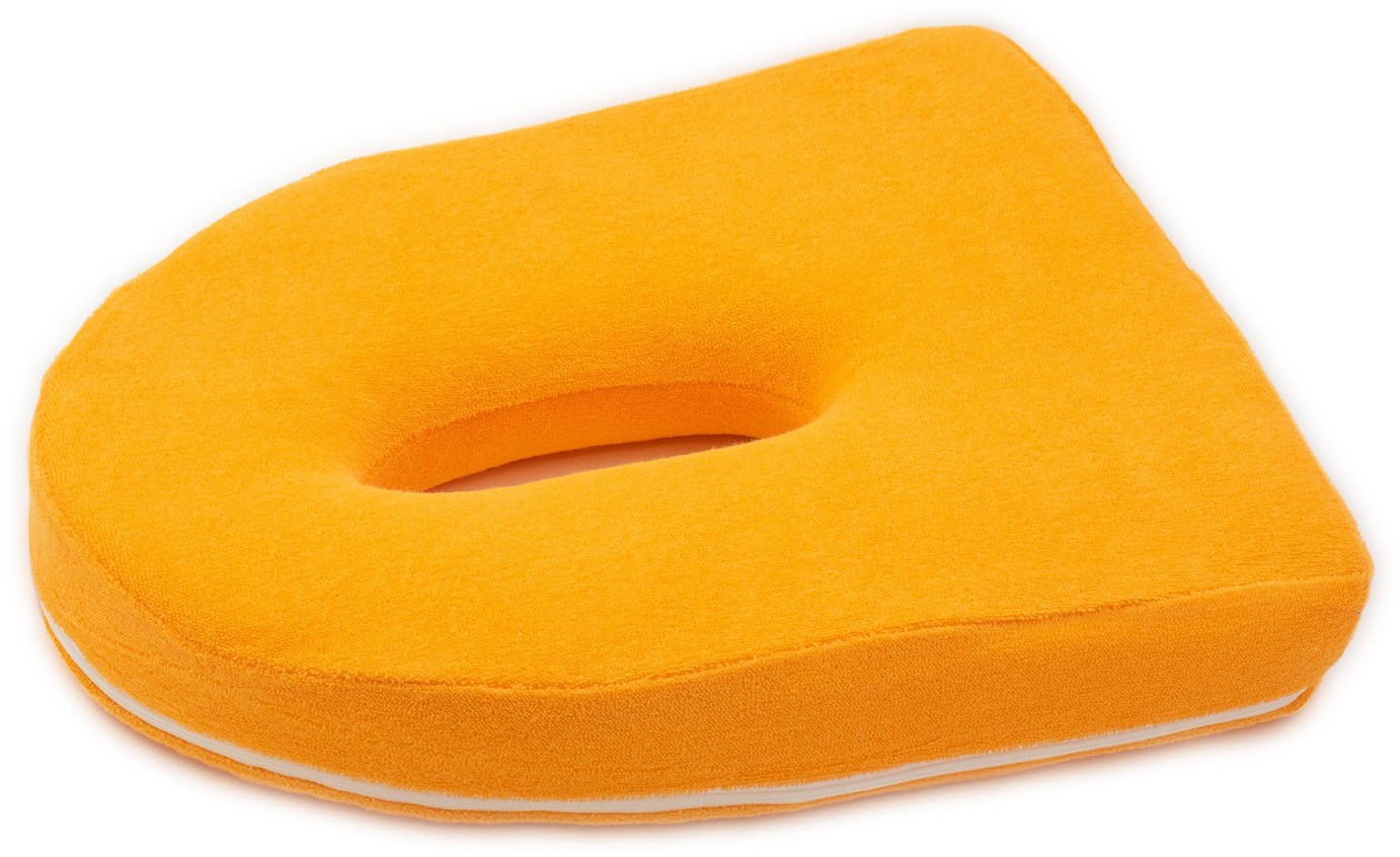Orangefarbenes, weiches Bauchlagekissen mit ovaler Aussparung als Gesichtsauflage. Mit abnehmbarem Bezug (weisser Reissverschluss seitlich) und ergonomischer Form für Komfort auf der Therapieliege.