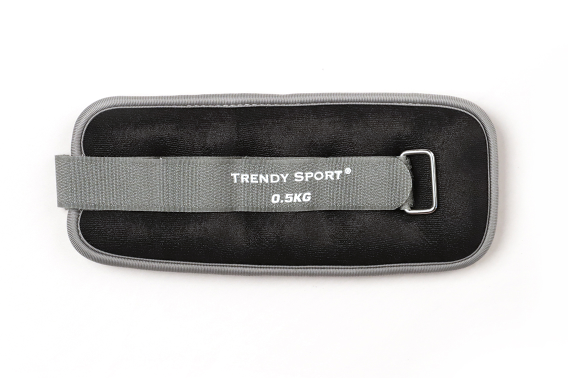 Polsino zavorrato nero con bordo grigio e chiusura in velcro grigia su fondo bianco. Sulla chiusura è riportata la scritta "Trendy Sport" e "0,5 kg". Per polsi o caviglie, per terapia e allenamento.