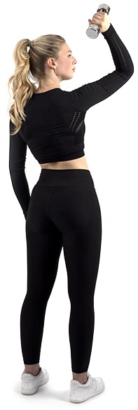 Jeune femme blonde en queue de cheval, en haut de sport noir et legging, s'entraîne avec un haltère chromé argenté. Elle fait une flexion des bras et regarde sur le côté. Exercice de musculation ciblé.