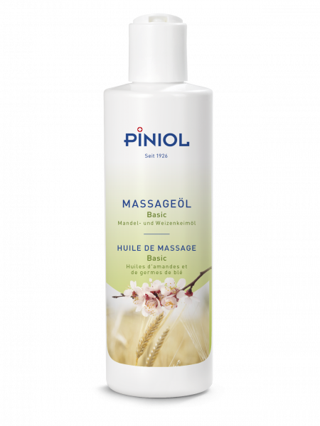 White ‘ Piniol ’ massage oil bottle with the words ‘Basic Almond and Wheat Germ Oil’ printed on it. Label featuring pink almond blossoms and golden ears of wheat on a green and white background. White flip-top cap, giving a natural, nourishing impression.