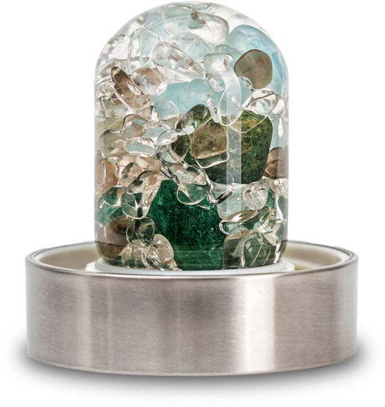 Gemstone insert for a water bottle, filled with cut rock crystals, amethysts and rose quartz. Transparent glass body containing irregularly shaped stones in clear, light purple and pale pink colours, with a metal ring at the base.