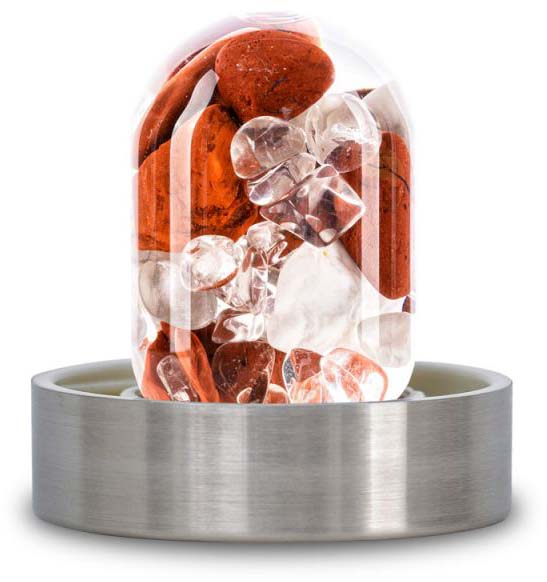 A transparent glass insert for a water bottle, filled with gemstones. It features clear, cut rock crystals as well as reddish-brown, partly rough rose quartz and pieces of amethyst. Set in a brushed metal frame.
