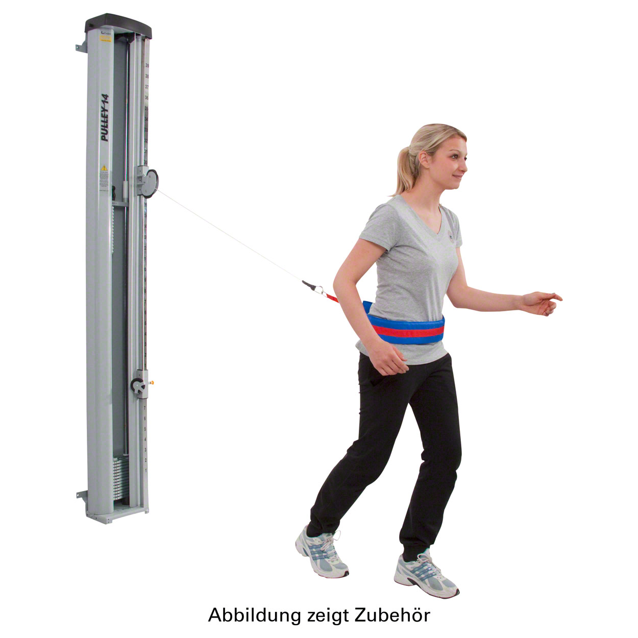 A woman in sportswear is training on a cable machine. She is wearing a padded pelvic belt in blue and red, connected to the machine by a cable. By taking a lunge forwards, she mobilises and strengthens her pelvis.