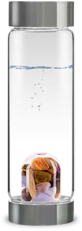 A tall, slender drinking bottle made of clear borosilicate glass with a silver-grey lid and matching base. Two-thirds full of clear water, with rising air bubbles. Separate compartment containing polished gemstones.