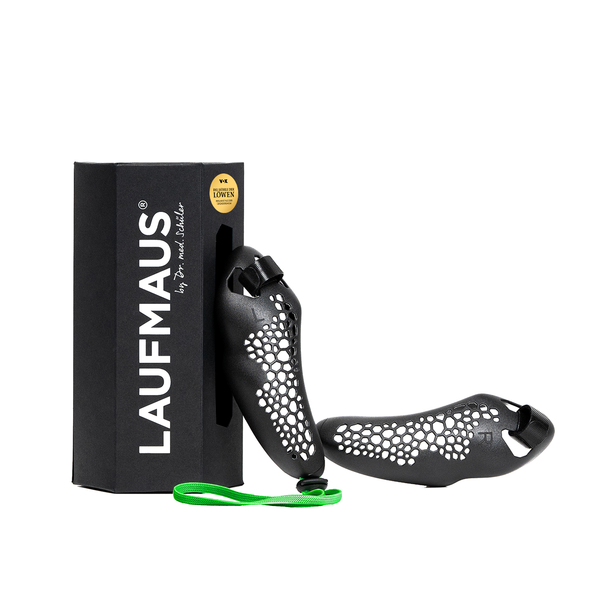 Deux souris gamer noires ergonomiques à motif alvéolé. L’une est verticale près de l’emballage noir avec autocollants « LAUFMAUS » et « DIE HÖHLE DER LÖWEN ». L’autre est devant. Un ruban vert les relie.