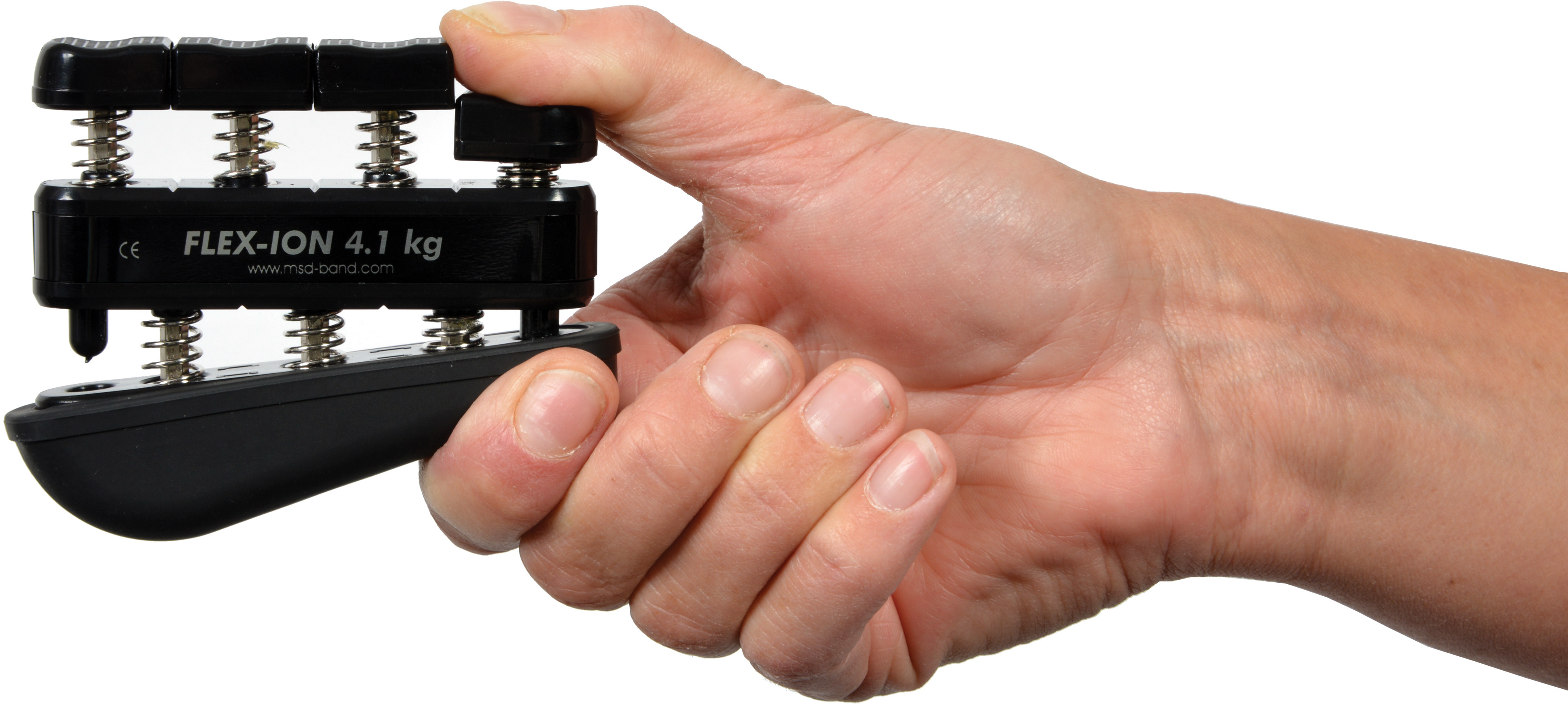 One hand is holding a black Moves Flex-Ion hand trainer with four spring-loaded buttons. Fingers press the buttons to strengthen the hand muscles. The inscription ‘FLEX-ION 4.1 kg’ is visible. For rehabilitation following hand injuries.
