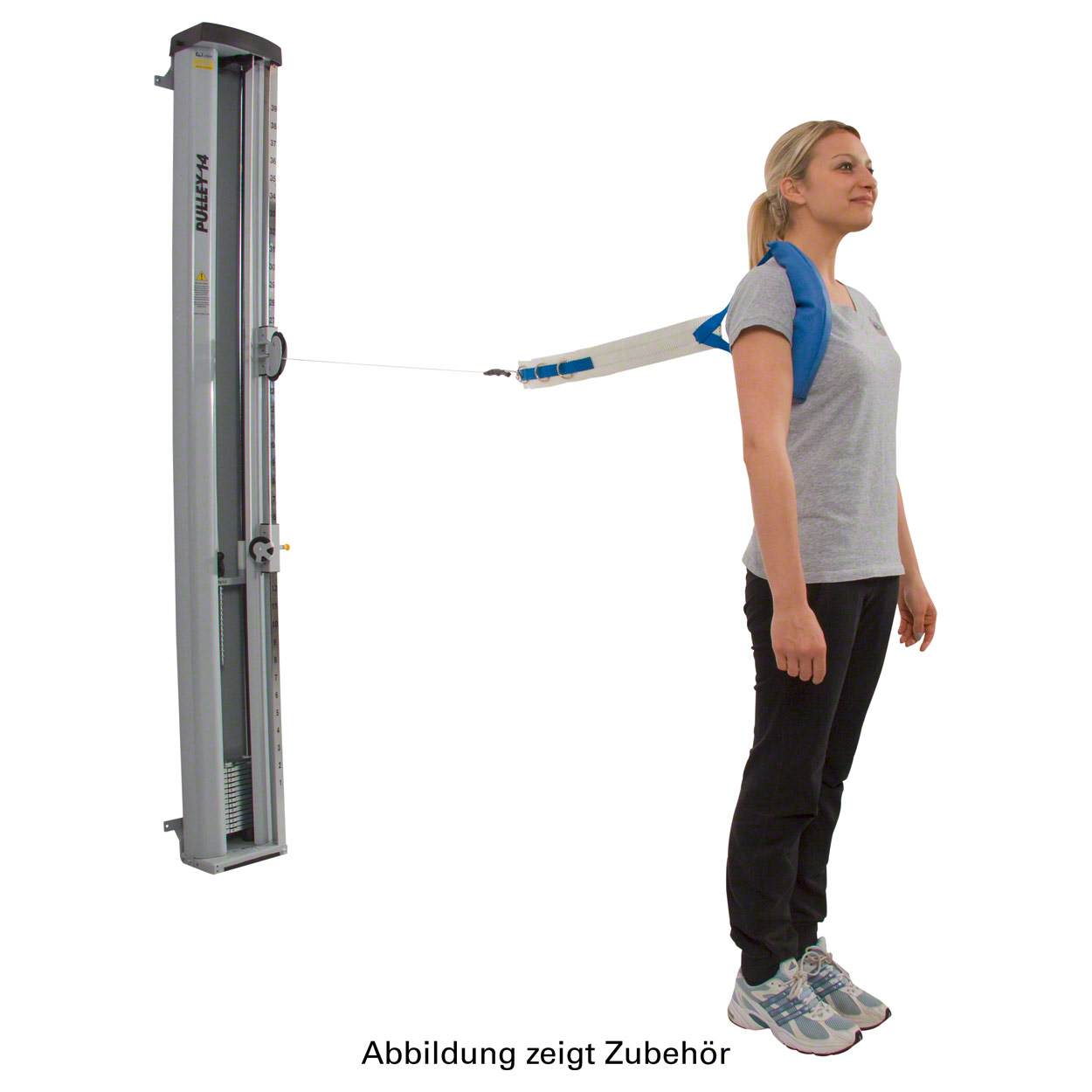 A young woman demonstrates how to use a blue, padded shoulder strap for cable exercises. The strap is attached to a grey, vertical cable machine with weights and the inscription ‘PULLEY-14’. She is standing to the side.