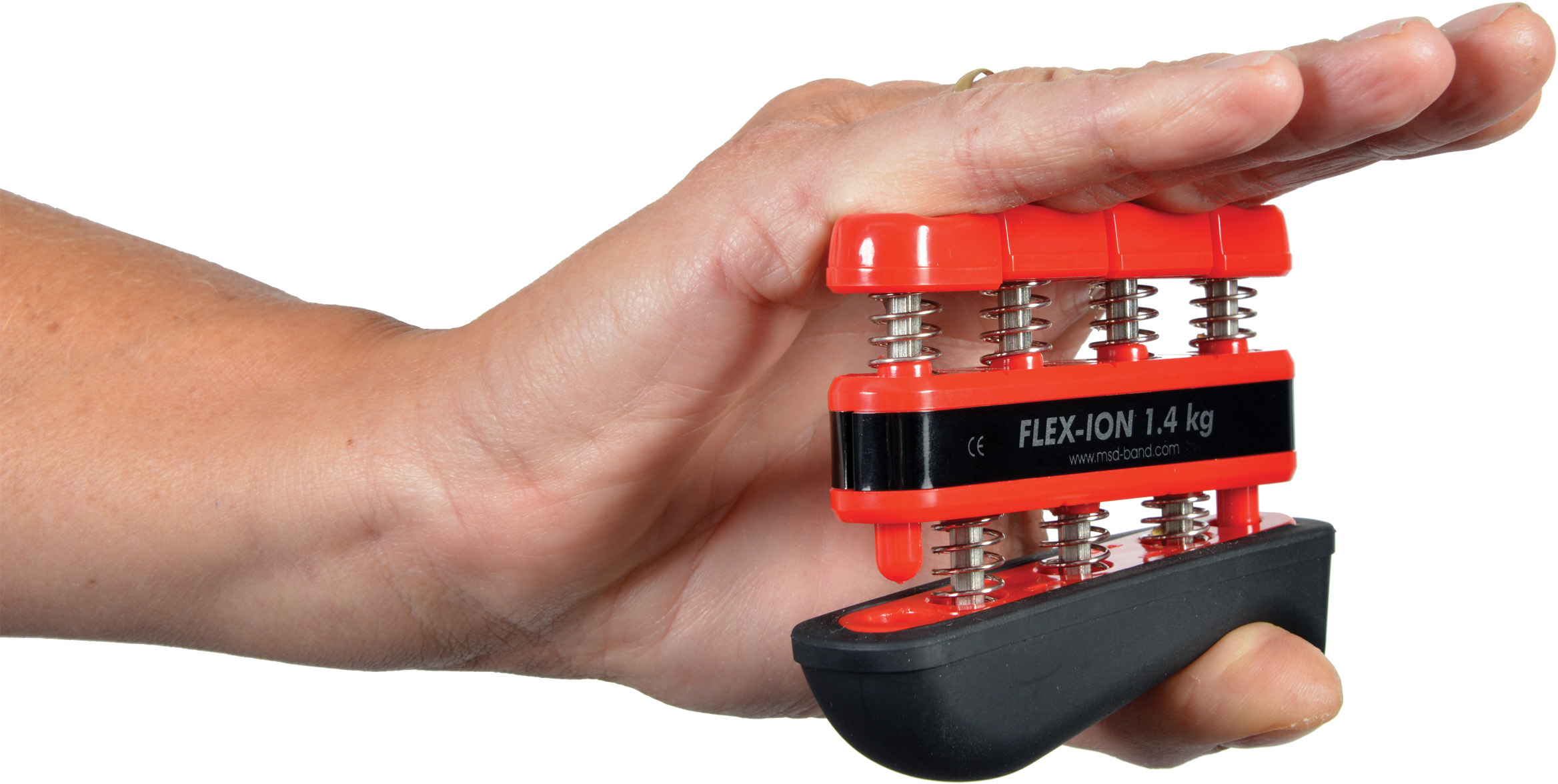 One hand is holding a red and black Moves Flex-Ion hand trainer with four spring-loaded buttons for targeted training of individual fingers. Inscription: ‘FLEX-ION 1.4 kg’ (resistance). Product shown in isolation against a white background.