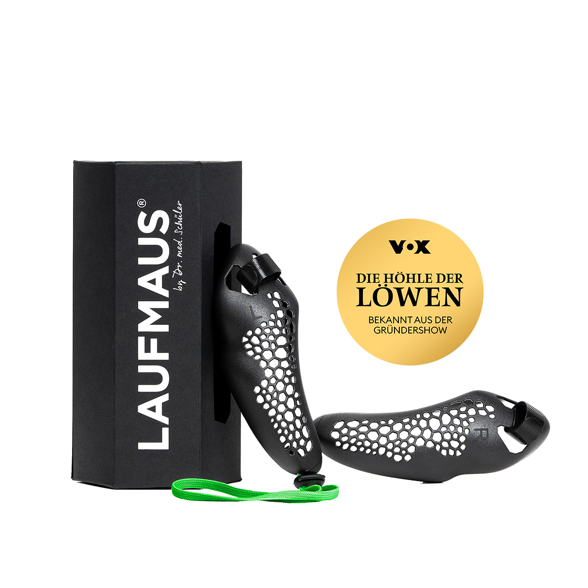Deux poignées noires et ergonomiques pour la Laufmaus en plastique spécial, avec alvéoles nid d'abeille. L'une près de l'emballage noir « LAUFMAUS » et d'une dragonne verte, l'autre posée à côté. Emblème doré « Die Höhle der Löwen ».