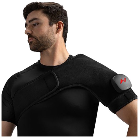A man is wearing a black Hyperice Venom 2 massage belt on his left shoulder and upper arm for targeted vibration and heat therapy. A grey control unit with a red logo is visible on his upper arm. Tight-fitting clothing emphasises the snug fit.