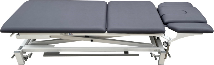 Dark grey, multi-section treatment couch with a light-coloured scissor-lift frame. The adjustable headrest features a face opening and armrests. Sturdy frame for easy height adjustment, ideal for medical practices, healthcare and therapy.